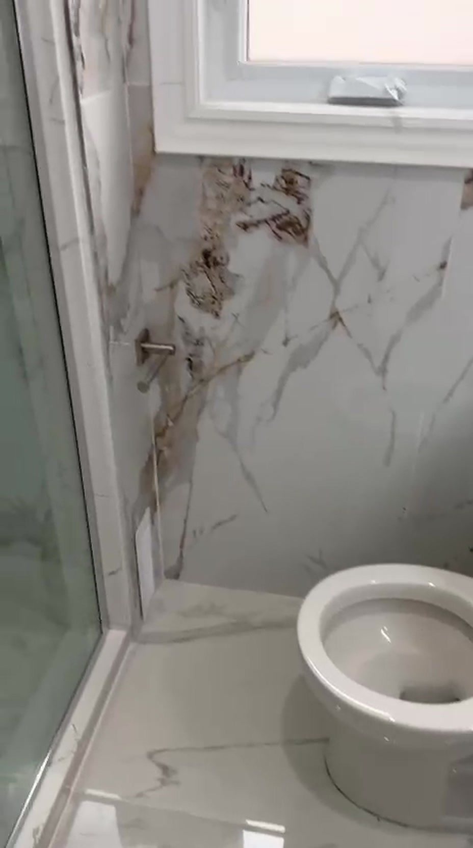 Finished Toronto bathroom renovation with gold-veined marble tile walls, a glass shower enclosure and a bright window
