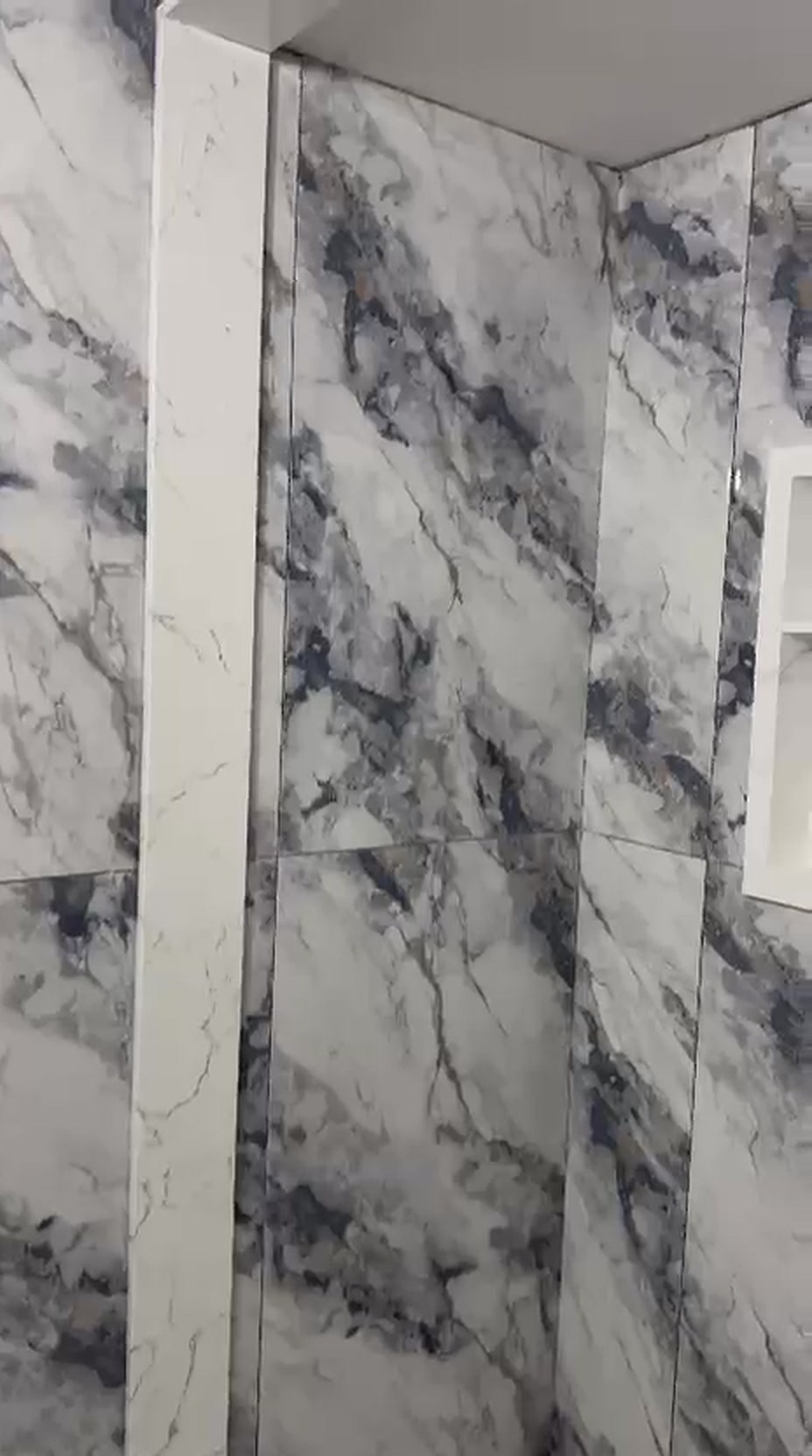 Recessed shower niche framed in crisp white trim set into grey-veined marble tile in a Vaughan bathroom renovation
