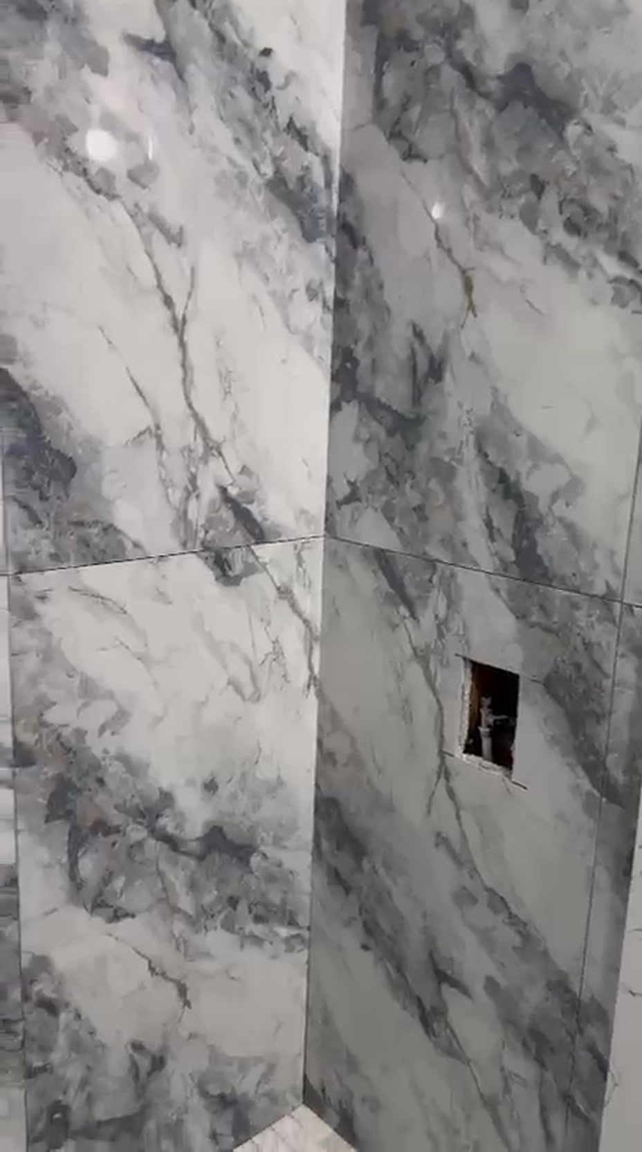 Large-format grey and white marble tile set with tight grout lines around a corner shower in a Vaughan renovation
